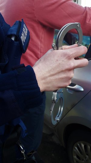 funkcjonariusz trzymający kajdanki w dłoni